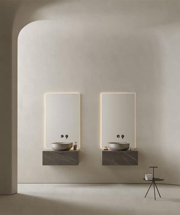 Dois móveis individuais de parede com duas gavetas e lavatórios redondos de montagem superior em mármore cinza. Espelhos Strato com iluminação LED. Inbani, Grate
